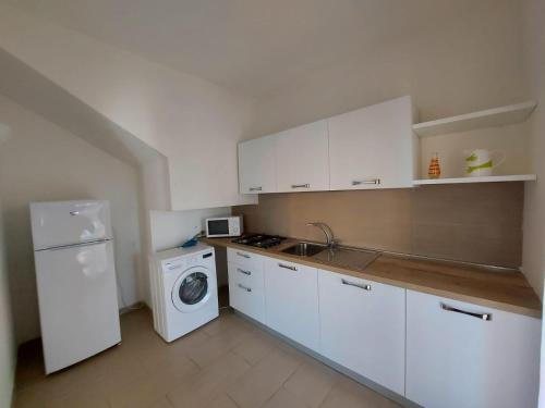 a kitchen with white cabinets and a washer and dryer at Villa Sirenetta in Cuile Pazzoni