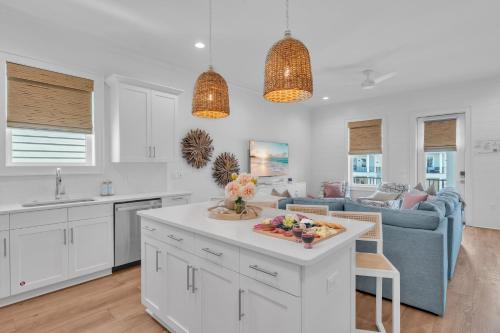a kitchen and living room with white cabinets and a blue couch at The Hangout House Relaxed 4BR Luxury, 3 King Suites, Walk to Beach, Pet Friendly in Gulf Shores