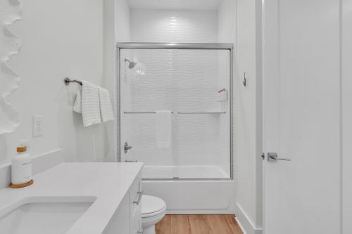a white bathroom with a shower and a toilet at The Hangout House Relaxed 4BR Luxury, 3 King Suites, Walk to Beach, Pet Friendly in Gulf Shores