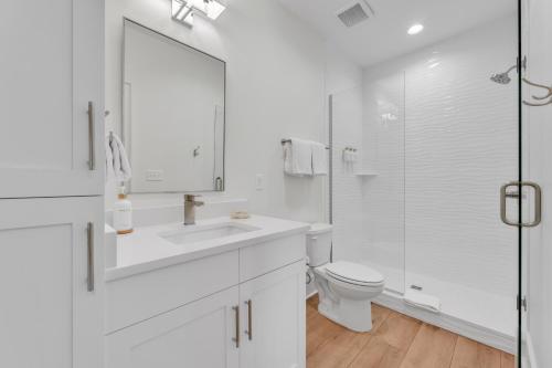 a white bathroom with a sink and a toilet at The Hangout House Relaxed 4BR Luxury, 3 King Suites, Walk to Beach, Pet Friendly in Gulf Shores