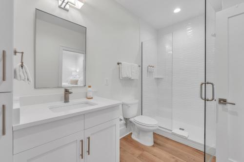 a white bathroom with a toilet and a glass shower at The Hangout House Relaxed 4BR Luxury, 3 King Suites, Walk to Beach, Pet Friendly in Gulf Shores