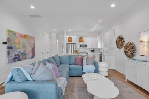 a living room with a blue couch and a kitchen at The Hangout House Relaxed 4BR Luxury, 3 King Suites, Walk to Beach, Pet Friendly in Gulf Shores