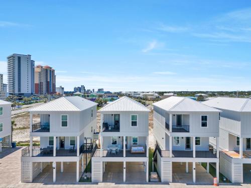 a row of white houses on the beach at The Hangout House Relaxed 4BR Luxury, 3 King Suites, Walk to Beach, Pet Friendly in Gulf Shores