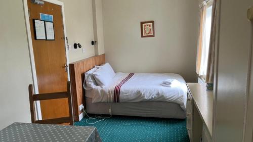a small bedroom with a bed and a door at Lavelle's Seaside House & Mickey's Bar in Achill Sound