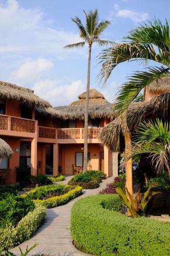 a resort with palm trees and a walkway at La Posada Hotel Boutique in Manzanillo