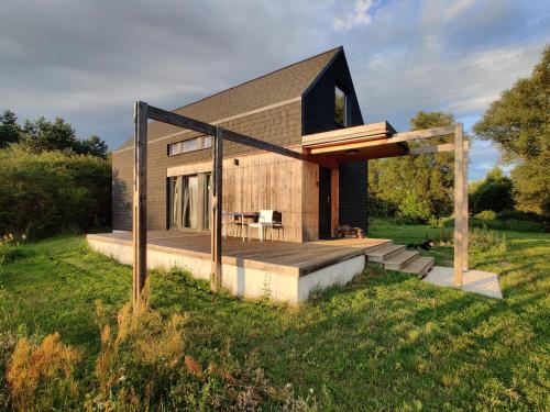 a house with a wooden deck on a field at Dom Szumią Wierzby in Szumlin