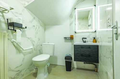 a white bathroom with a toilet and a sink at La Villa Cassinne Chambres Indépendantes in Montebourg