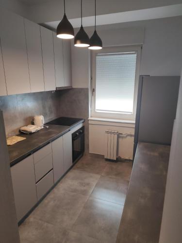 a small kitchen with white cabinets and a window at Gigabit High-Speed Internet Modern Apartment in Skopje