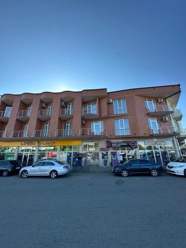 un grand bâtiment avec des voitures garées dans un parking dans l'établissement Kobuleti, Rustaveli street 3, à Itʼkhvisi