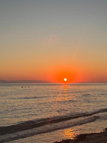 a sunset over the ocean with people in the water at Luxury Apartment Bedro in Nea Kalikratia
