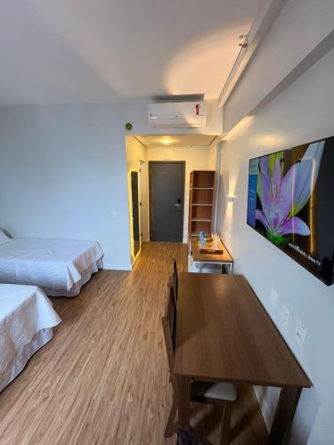 a bedroom with a bed and a table and a tv at Helbor Stay Gonzaga - Suíte moderna a 5 min da praia in Santos