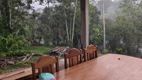 a wooden table and chairs with a view of a forest at Refúgio na Floresta in Manaus