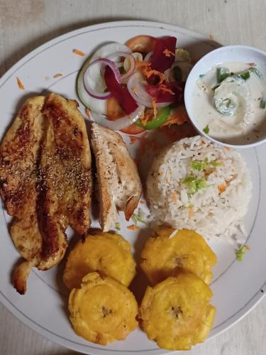a plate of food with chicken and rice and vegetables at Eco lodge finca magdalena in Altagracia
