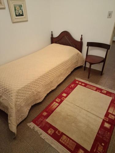 a bedroom with a bed and a chair and a rug at Apto Fofo com Natureza em Serra Negra in Serra Negra