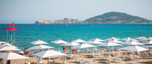 a bunch of white umbrellas on a beach with the ocean at Casa Vacanze Torre di Mola in Formia