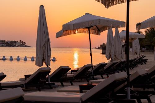 a group of lounge chairs and umbrellas on a beach at Shades Beach Club in Jeddah