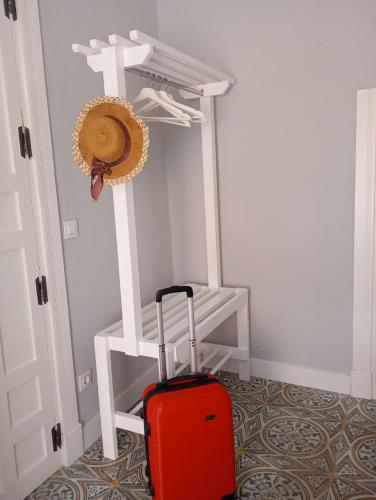 a red suitcase in a room with a cross and a hat at Apartamento Trasiego in Valdepeñas
