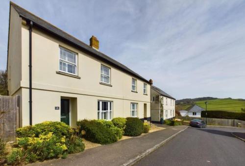 a white house with a car parked in the driveway at Charmouth Sea House by the beach in Charmouth