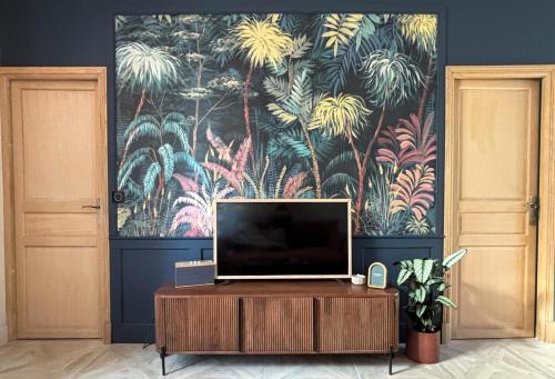 a tv on a table in a room with a painting at Ô Bulles de Loire, Châteauneuf-sur-Loire in Châteauneuf-sur-Loire