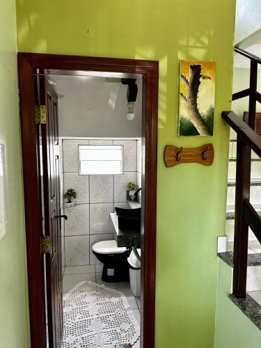 a bathroom with a toilet and a green wall at Casa em Alter do chão - lago verde in Alter do Chao