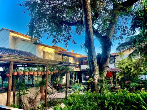 a house with a tree in front of it at Pousada Bon Vivant in Cabo Frio