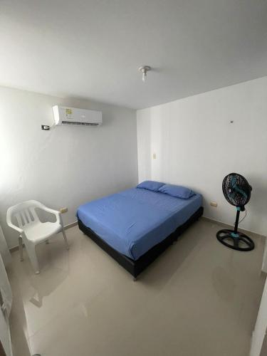 a bedroom with a blue bed and a white chair at Vacaciones Inolvidables in Coveñas