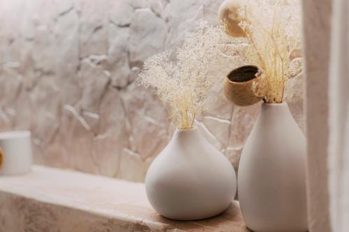 two white vases sitting on a counter with flowers at Lindos Zen luxury villa in Líndos