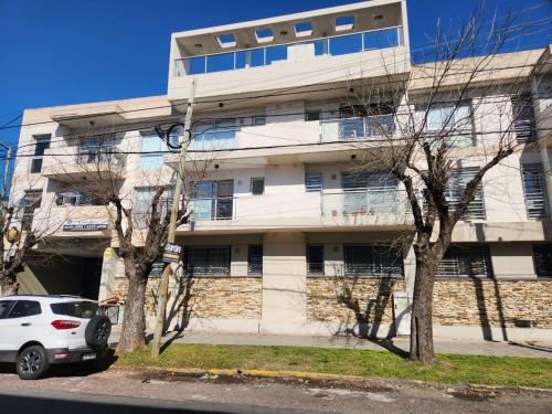une voiture blanche garée devant un immeuble dans l'établissement Departamento Banfield Centro, à Lomas de Zamora