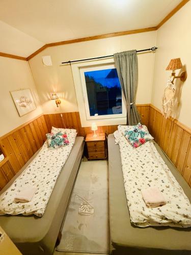 two beds in a small room with a window at Rifi Senja House in Senja