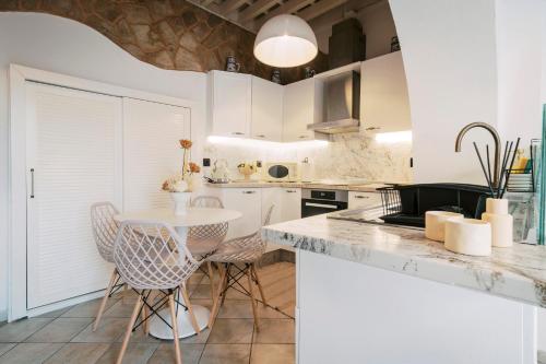 a kitchen with white cabinets and a table and chairs at Lindos Zen luxury villa in Líndos