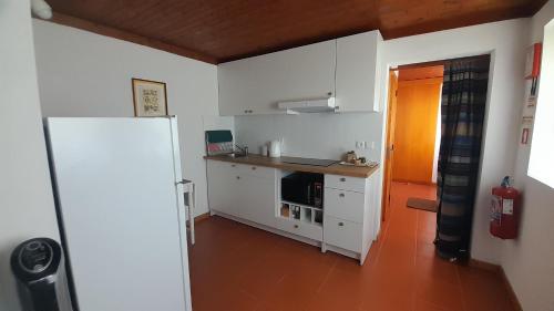 a small kitchen with white cabinets and a refrigerator at Casa da Tília in Caxarias