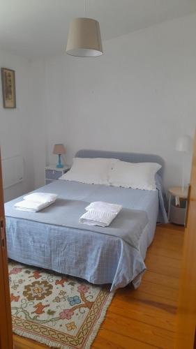 a bedroom with a bed with a blue blanket and a rug at Casa da Tília in Caxarias