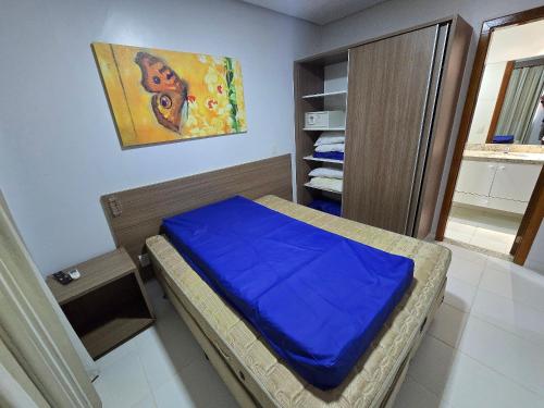 a bedroom with a bed with a blue blanket on it at Apartamentos em Rio Quente com maravilhosa área de lazer e excelente localização in Rio Quente