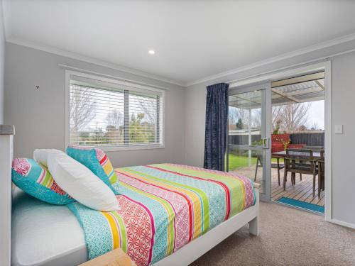 um quarto com uma cama e uma porta de vidro deslizante em Golden Vista - Coromandel Holiday Home em Coromandel Town