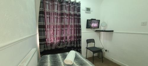 a room with a bed and a chair and a curtain at Starlet Single Room in Manchester
