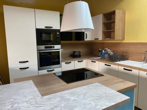 eine Küche mit weißen Schränken und einem Herd mit Backofen in der Unterkunft La Chaumine des Épicuriens Garden Parking in Saint-Hilaire-Saint-Mesmin