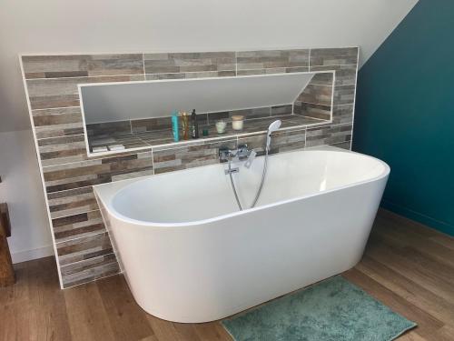 eine weiße Badewanne im Bad mit Spiegel in der Unterkunft La Chaumine des Épicuriens Garden Parking in Saint-Hilaire-Saint-Mesmin