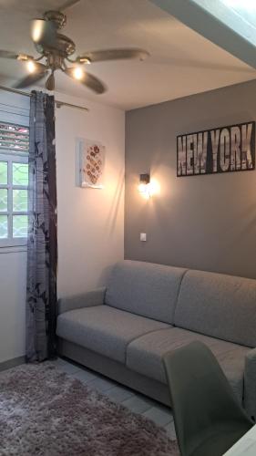a living room with a couch and a new york sign on the wall at Grand F2, spa, jardin, parking in Schœlcher