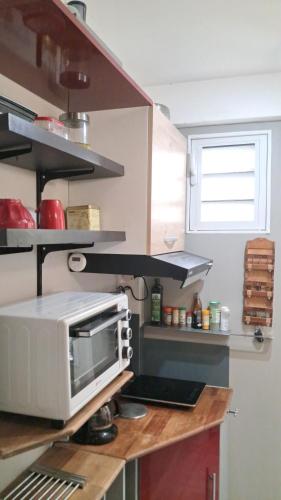a kitchen with a microwave on top of a counter at Grand F2, spa, jardin, parking in Schœlcher
