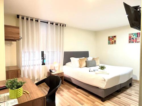 ein Schlafzimmer mit einem Bett, einem Schreibtisch und einem Tisch in der Unterkunft Terraza Hotel Bogota in Bogotá