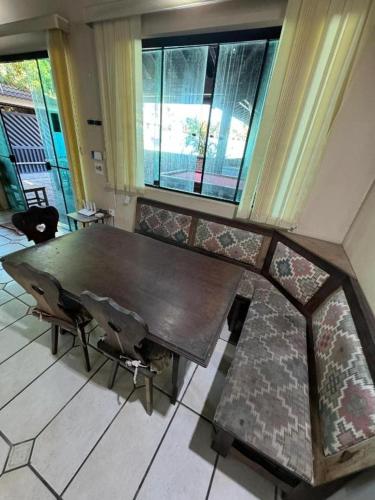 a wooden table and chairs in a room with windows at Pousada Pérolas de Peruíbe in Peruíbe