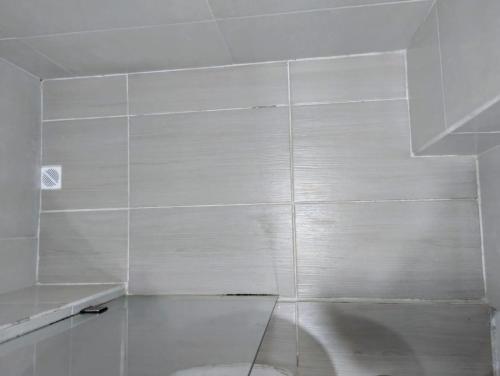 a white tiled wall in a bathroom with a toilet at Habitación con cama queen y baño privado cerca del parque in La Ceja