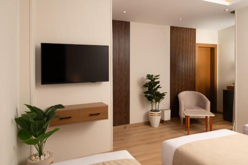 a room with a tv on a wall with a bed and a chair at Giza Capital Hotel in Cairo