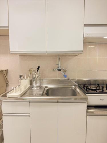 een keuken met witte kasten en een spoelbak bij Ahyeon Station 10-minute walk Cozy Stay in Seoul