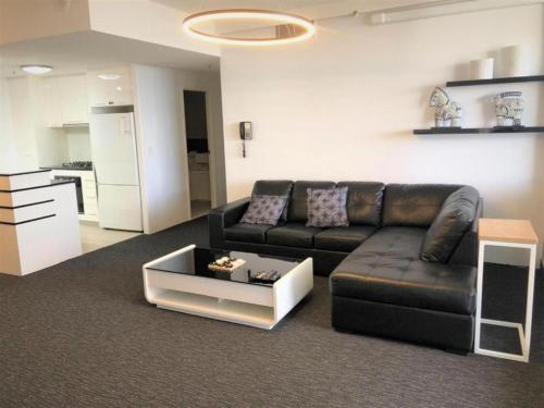 a living room with a leather couch and a coffee table at Tweed Ultima Apartments in Tweed Heads