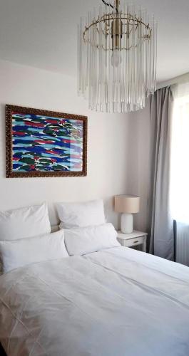 a bedroom with a white bed and a chandelier at Suite D in Bad Dürkheim