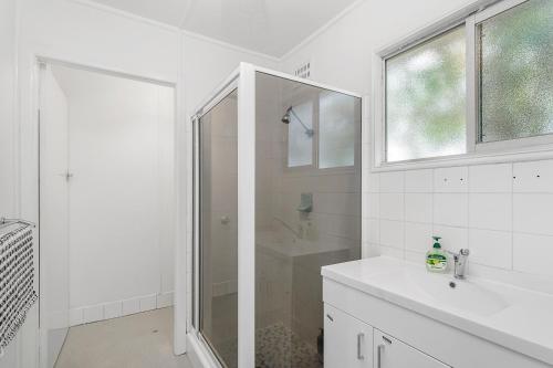 a white bathroom with a shower and a sink at Beach Shack No. 5 in Crescent Head