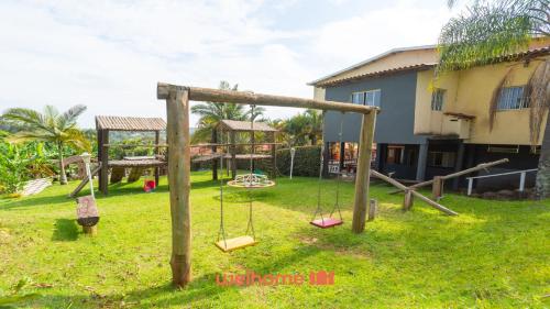 a playground with swings in a yard with a house at Casa ampla em Mairinque com lazer completo in Mairinque