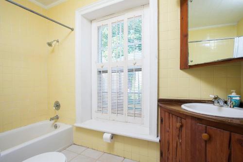 a bathroom with a tub and a sink and a window at Tamarind home in Governorʼs Harbour
