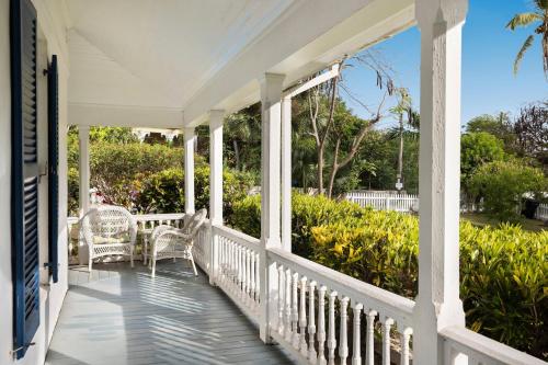 a white porch with two chairs and trees at Tamarind home in Governorʼs Harbour